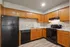 Inviting kitchen with sleek black appliances, elegant wood cabinetry, and a seamless marble countertop finish.