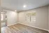 Bright and inviting room with elegant wooden flooring, large window for natural light, and modern recessed lighting.