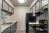 Modern kitchen featuring sleek black appliances, elegant granite countertops, and stylish grey cabinetry for a sophisticated appeal.