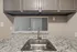 Modern kitchen corner with elegant granite countertops, sleek stainless steel sink, and stylish grey cabinets, offering a refined and functional space.