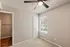 Bright cozy bedroom with fresh carpeting, elegant ceiling fan, and natural light from a large window.