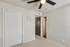 Bright interior room featuring a ceiling fan, closed cupboard, and open bathroom door, showcasing a cozy and inviting space.