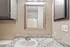 Chic bathroom with elegant granite countertop, modern sink, and stylish wooden-framed mirror, complemented by neutral-toned cabinets.