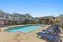 Inviting apartment community courtyard featuring a sparkling swimming pool surrounded by comfortable lounge chairs and charming townhouse-style apartments.