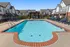 Inviting community pool surrounded by modern townhouses and comfortable lounge chairs, perfect for relaxation and leisure.