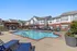 Inviting apartment complex showcasing a sparkling outdoor pool surrounded by comfortable lounge chairs, perfect for relaxation and social gatherings.