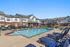 Inviting apartment complex with a sparkling outdoor pool, surrounded by comfortable lounge chairs, perfect for relaxation and leisure.