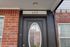 Charming entrance with a sleek black door featuring an elegant oval glass insert, set against a classic red brick exterior.