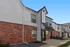 Charming two-story townhouse with brick and siding exterior, showcasing modern architectural design under a clear blue sky.