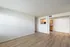 Bright and open living space featuring modern laminate flooring and a view into a cozy, well-lit kitchen area.