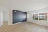 Bright living area with sleek wood flooring, a feature wall, and large windows offering natural light.