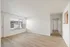 Bright and spacious living area with large window, sleek hardwood floors, and modern white walls.