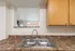 Modern kitchen area showcasing a sleek dual sink, granite countertops, and wooden cabinets, perfect for culinary enthusiasts.