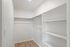 Spacious walk-in closet with sleek wooden floors and ample shelving for organized living.