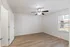 Bright, airy bedroom with sleek wood flooring, modern ceiling fan, and ample natural light from large window.