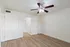 Bright, airy bedroom with elegant ceiling fan, showcasing modern wood flooring and pristine white walls.