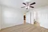 Bright and airy bedroom with modern ceiling fan, sleek laminate flooring, and an adjoining bathroom entry.