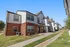 Charming modern townhouses with classic brick and siding exteriors, nestled in a peaceful neighborhood with well-maintained lawns.