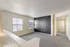 Bright and inviting living space with large windows, plush carpeting, and a modern accent wall, leading to a spacious hallway.