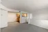 Spacious and bright open-concept living area with plush carpeting and a view into a modern kitchen featuring wooden cabinetry.