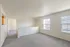 Bright, spacious living area with large windows, plush carpeting, and a welcoming atmosphere, ideal for relaxation.