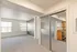 Bright living space with large windows, featuring plush carpet and a sleek kitchen with modern appliances.