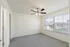 Bright and airy bedroom with soft carpeting, large windows offering natural light, and a stylish ceiling fan.