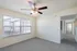 Bright and airy room with a modern ceiling fan, large window with blinds, and plush carpet, perfect for comfortable living.