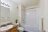 Bright and modern bathroom with elegant granite countertop, large mirror, and pristine bathtub in a stylish apartment.