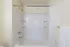 Bright and modern bathroom featuring a pristine white bathtub with built-in shelving, complemented by a stylish shower curtain and a soft towel on the rack.