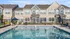 Charming apartment complex with modern double-story architecture, featuring a pristine swimming pool and cozy outdoor seating areas.