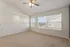 Bright and airy room with plush carpeting, large windows offering scenic views, and a modern ceiling fan.