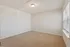Bright and airy room with plush carpeting, white walls, and a large window inviting natural light.
