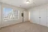 Bright and inviting empty room with plush carpeting, large sunny window, and modern white doors, perfect for customization and decorating.