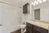 Modern bathroom with elegant granite countertop, stylish dark wood cabinetry, and a pristine white bathtub, offering a luxury retreat feel.