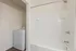 Bright and modern bathroom with sleek bathtub and in-unit laundry, offering convenience and style.