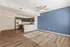Modern living space featuring an open-concept kitchen with stainless steel appliances, elegant wood flooring, and a stylish blue accent wall.