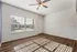 Bright and airy room with elegant wood flooring and abundant natural light from large windows, enhanced by a modern ceiling fan.