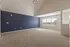 Spacious, light-filled room with plush carpeting, deep blue accent wall, and large windows offering scenic views.