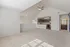 Bright, open-concept living area with vaulted ceiling, modern kitchen, and plush carpeted flooring, offering a spacious and inviting ambiance.