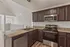 Charming kitchen with modern appliances, elegant dark wood cabinets, and spacious countertops, overlooking a bright open living area.