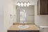 Modern bathroom with elegant granite countertop, stylish lighting, and a large mirror, leading to a sunlit room with a cozy window view.