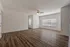 Spacious living room with elegant hardwood floors, large window for natural light, and modern ceiling fan.