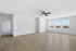 Bright and spacious living room with sleek wood flooring, large windows offering natural light, and a modern ceiling fan.
