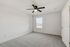 Bright and airy bedroom with plush gray carpeting, contemporary ceiling fan, and large window for natural light.