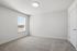 Bright and airy room with plush carpeting, large window allowing natural light, and modern white walls, perfect for a cozy living space.
