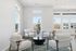 Bright and inviting lounge area with modern white armchairs, natural light flooding in through large windows, and a stylish round black coffee table.