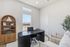 Bright and inviting home office with elegant wooden bookshelf, modern black desk, and cozy seating, perfect for productivity and comfort.