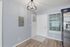 Elegant entryway with modern light fixture, sleek stainless steel fridge, and chic flooring, perfect for a welcoming home atmosphere.