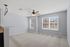 Bright and airy living room with plush carpeting, large windows, and a modern ceiling fan, perfect for enjoying natural light and comfort.